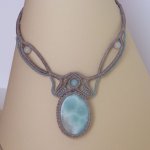 Ketting in taupegrijs/roestblauw micro-macramé met een natuurlijke edelsteen in zachte tinten wit en lichtblauw als middelpunt.
